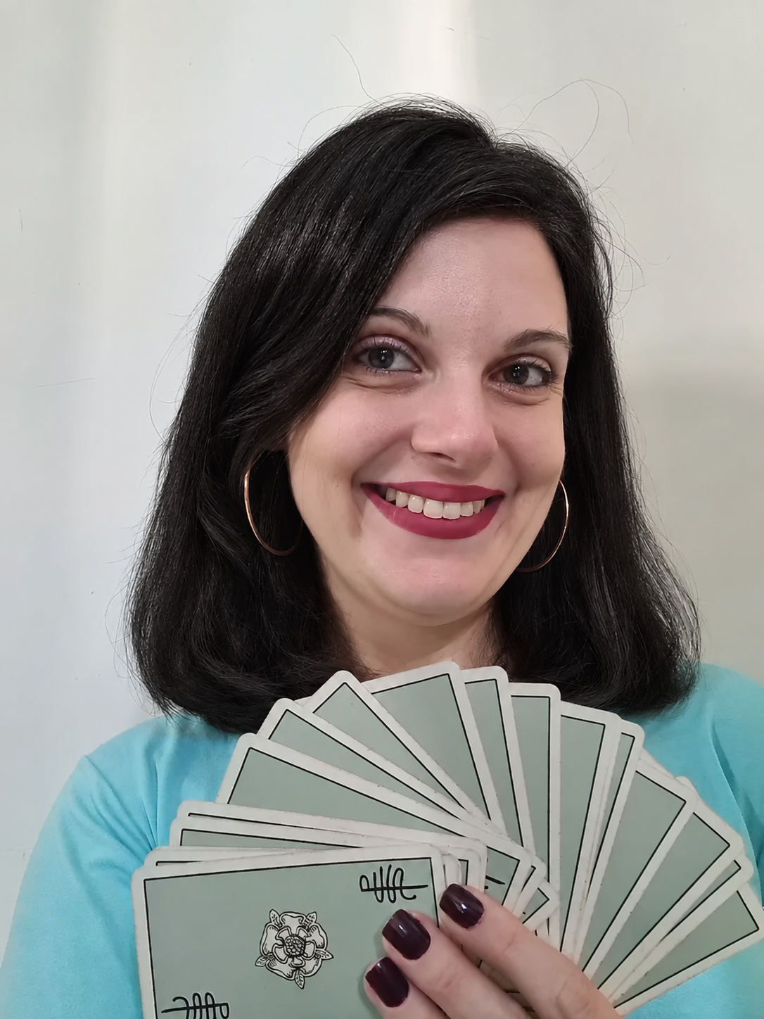 Erika Martire sorrindo e segurando cartas de Tarot